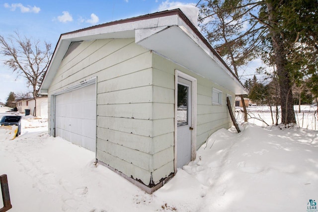 snow covered garage featuring fence