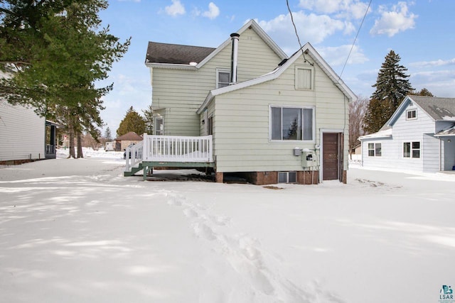 snow covered rear of property with a wooden deck