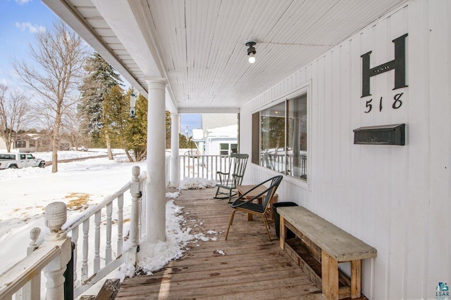 snow covered deck with a porch