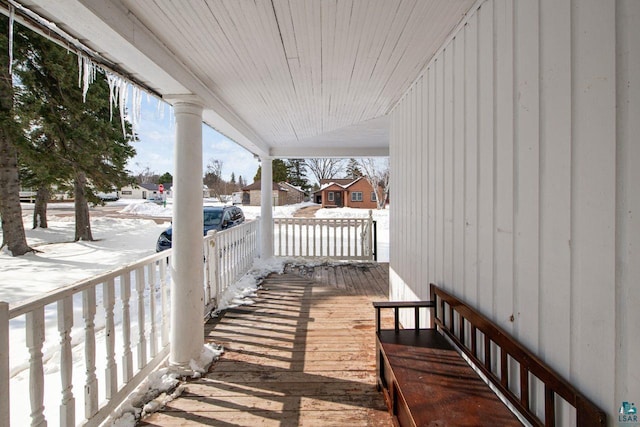 snow covered deck featuring covered porch and a residential view