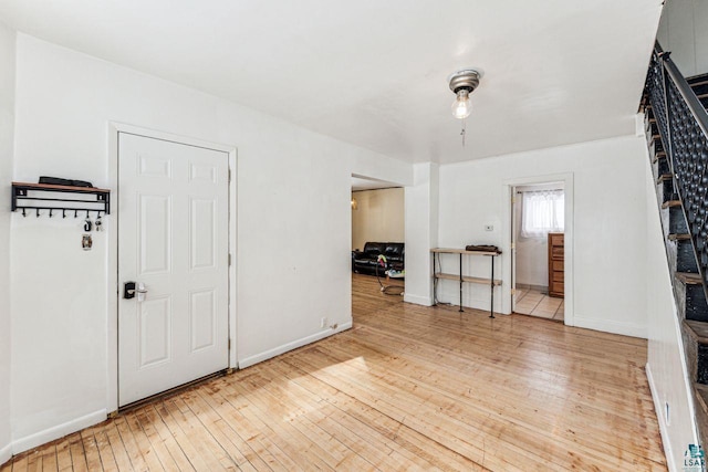 empty room featuring baseboards, hardwood / wood-style floors, and stairs