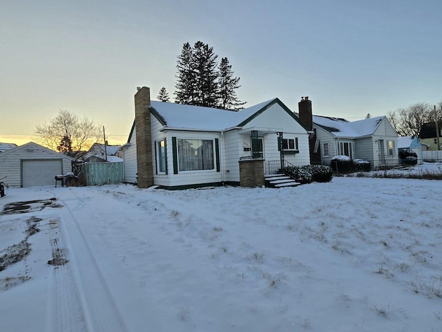 view of front of property featuring a chimney, a detached garage, and an outdoor structure