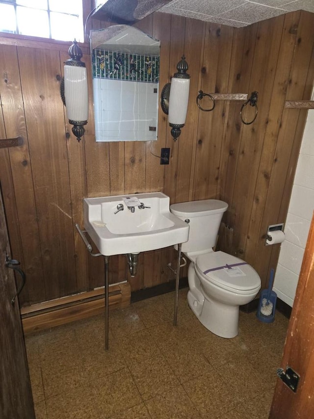 bathroom featuring tile patterned floors, toilet, and wooden walls