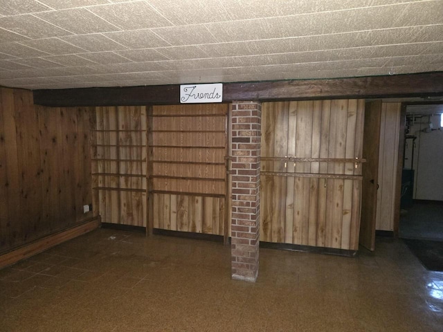 finished basement featuring wooden walls and tile patterned floors