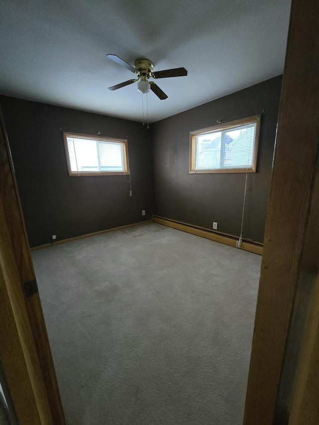 carpeted spare room featuring a baseboard radiator, ceiling fan, and baseboards