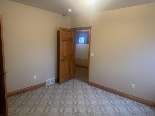 carpeted spare room with visible vents and baseboards