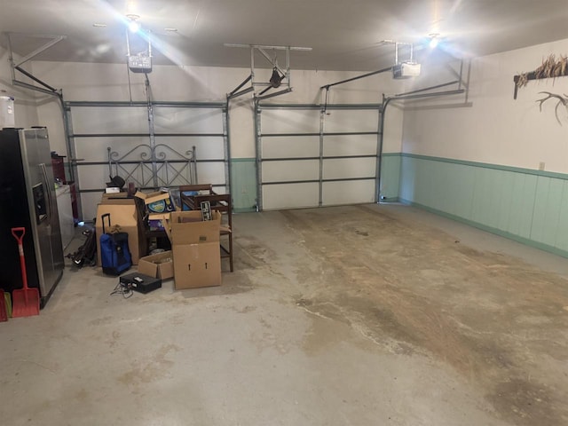 garage with stainless steel fridge and a garage door opener