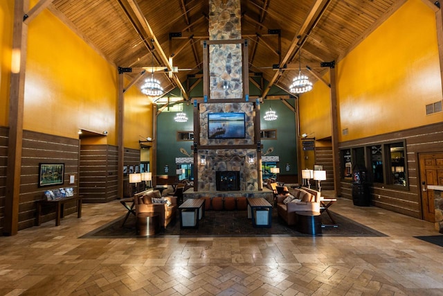 living room featuring visible vents, wood ceiling, a stone fireplace, high vaulted ceiling, and a notable chandelier