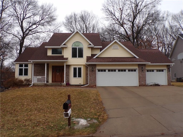 traditional-style home with brick siding, a porch, concrete driveway, a front yard, and an attached garage