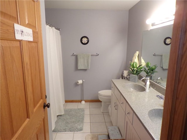 bathroom with tile patterned floors, toilet, double vanity, and a sink