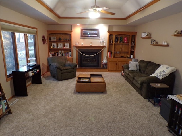 living room featuring a raised ceiling, built in shelves, a fireplace, and carpet floors