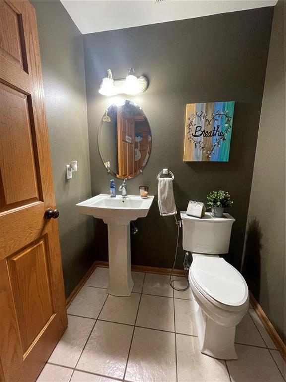 half bathroom featuring tile patterned floors, toilet, and baseboards