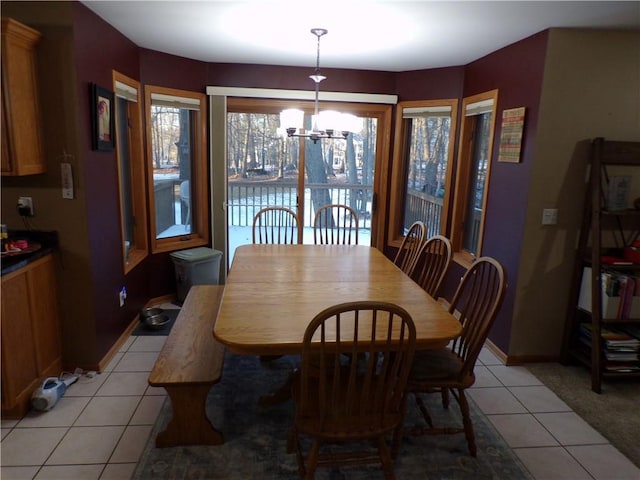 dining space with light tile patterned floors, baseboards, and a chandelier