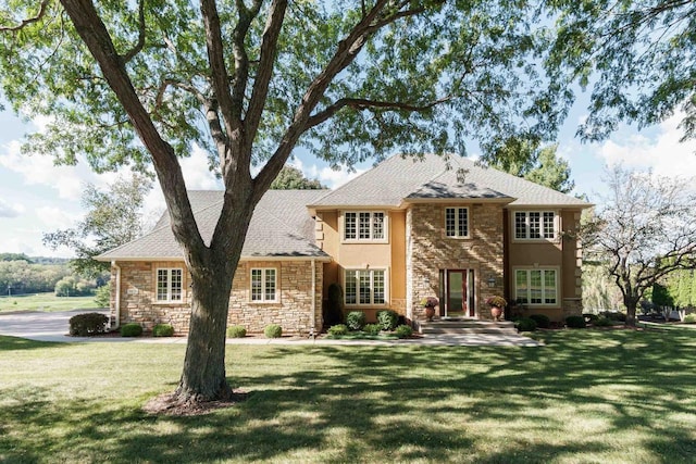 view of front of home featuring stucco siding, stone siding, and a front lawn