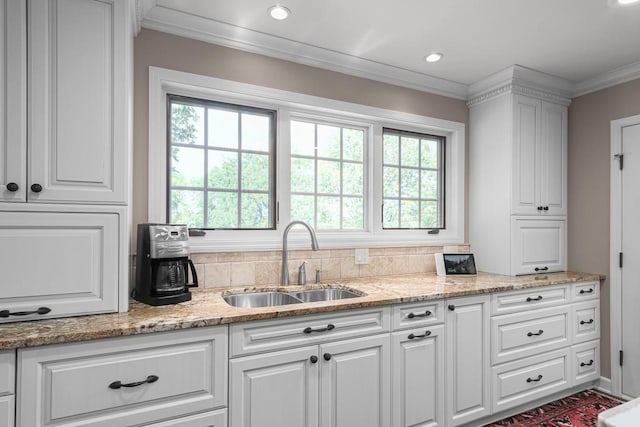 kitchen featuring white cabinets, ornamental molding, a wealth of natural light, and a sink