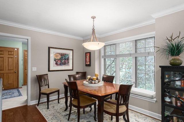 dining area with light wood-type flooring, crown molding, and baseboards