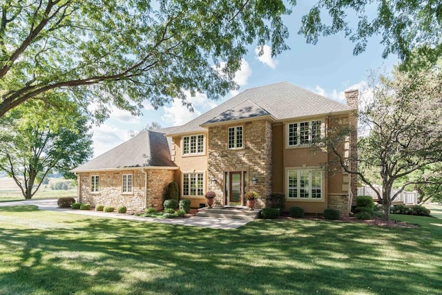 view of front of house with a front yard, stucco siding, stone siding, and a chimney