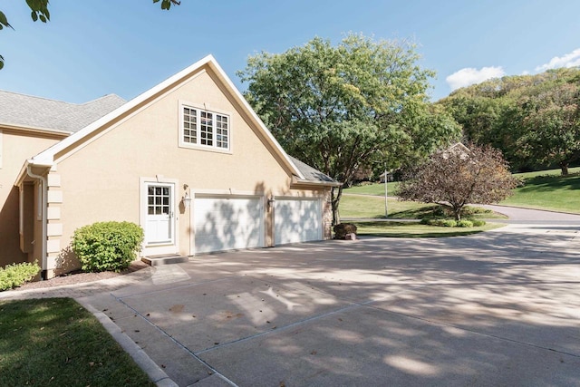 view of side of property featuring stucco siding, driveway, and a lawn