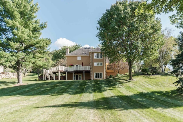 rear view of property with stairway, a wooden deck, a yard, stucco siding, and a chimney