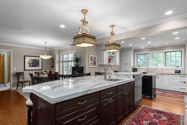 kitchen with ornamental molding, a sink, backsplash, white cabinets, and dishwasher