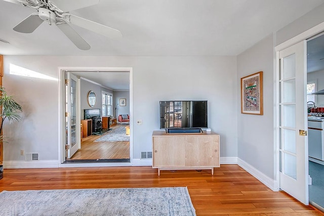 unfurnished living room with visible vents, ceiling fan, baseboards, and wood finished floors