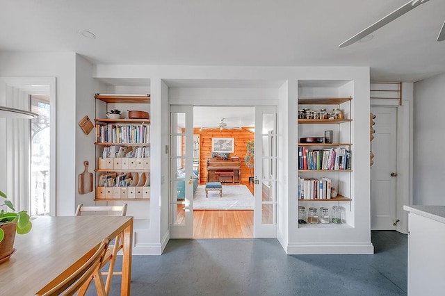 interior space featuring built in shelves, french doors, and concrete flooring