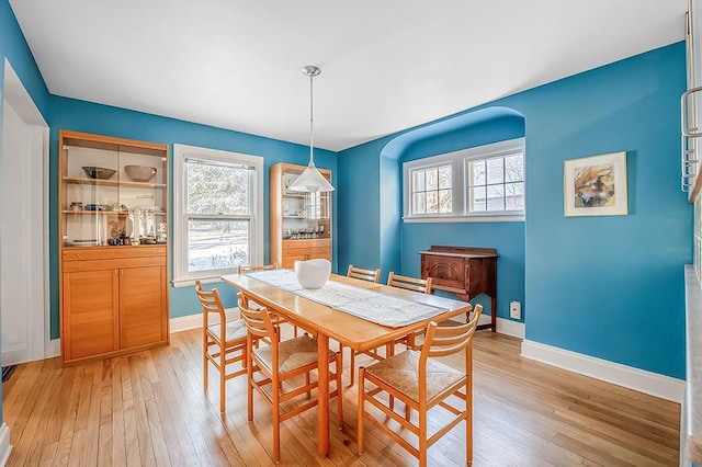 dining room featuring plenty of natural light, baseboards, and light wood-style floors