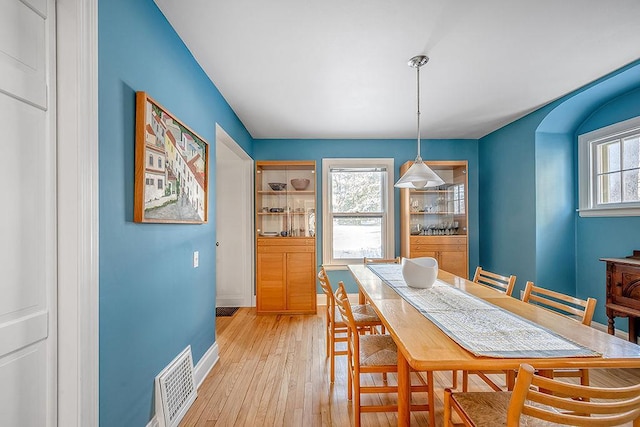 dining room with light wood finished floors, visible vents, a healthy amount of sunlight, and baseboards