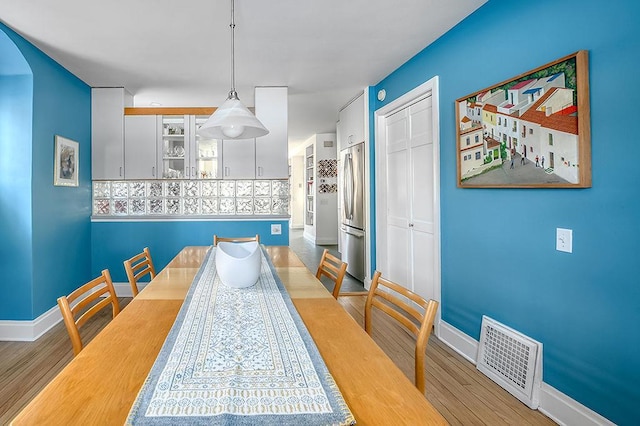 dining area featuring wood finished floors, visible vents, and baseboards