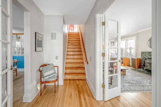 staircase featuring wood finished floors, a wood stove, plenty of natural light, and french doors