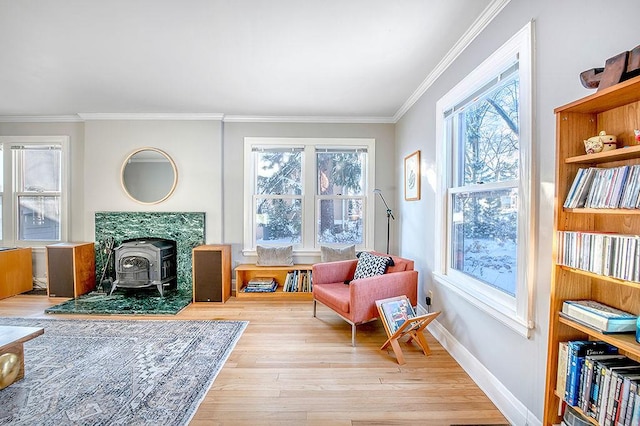 living area with baseboards, wood finished floors, ornamental molding, and a wood stove