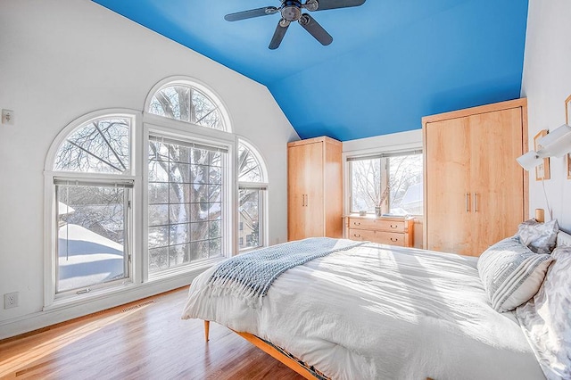 bedroom featuring lofted ceiling, multiple windows, wood finished floors, and visible vents