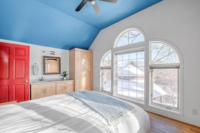 bedroom featuring a sink, lofted ceiling, wood finished floors, and a ceiling fan