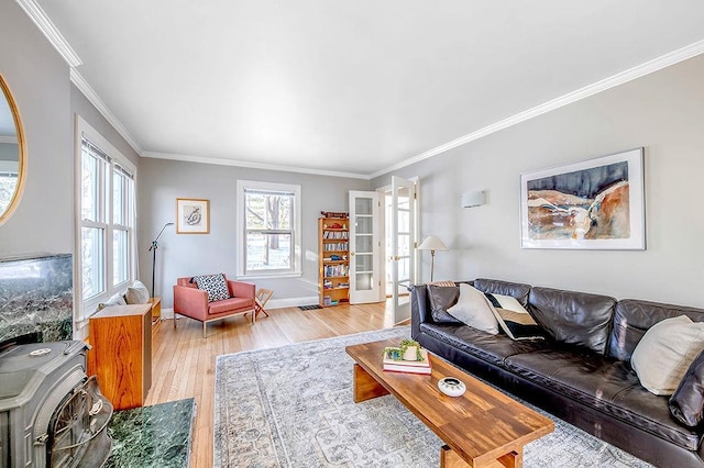 living area with light wood finished floors, french doors, baseboards, and ornamental molding