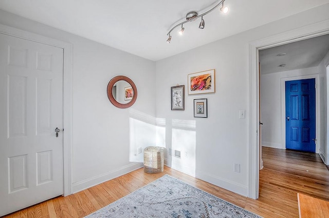 interior space with rail lighting, baseboards, and wood finished floors