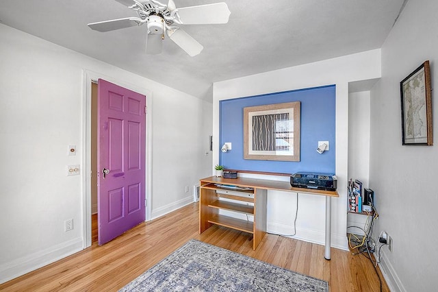 interior space with baseboards, wood finished floors, and a ceiling fan