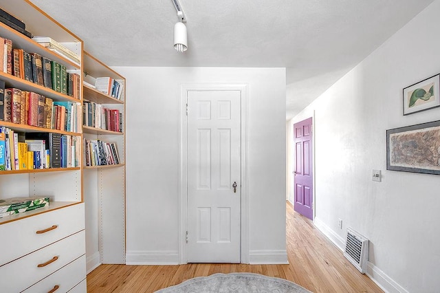 corridor with visible vents, baseboards, and light wood-style flooring