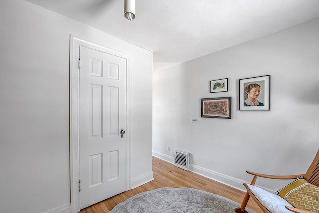 sitting room with light wood finished floors, visible vents, and baseboards