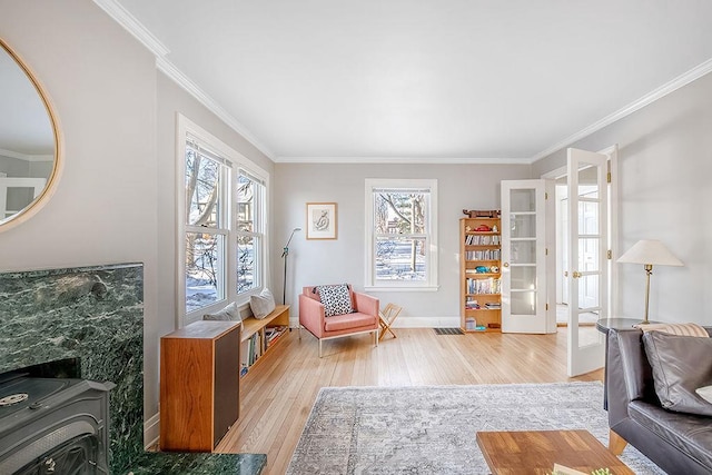 sitting room featuring light wood-type flooring, baseboards, a healthy amount of sunlight, and ornamental molding