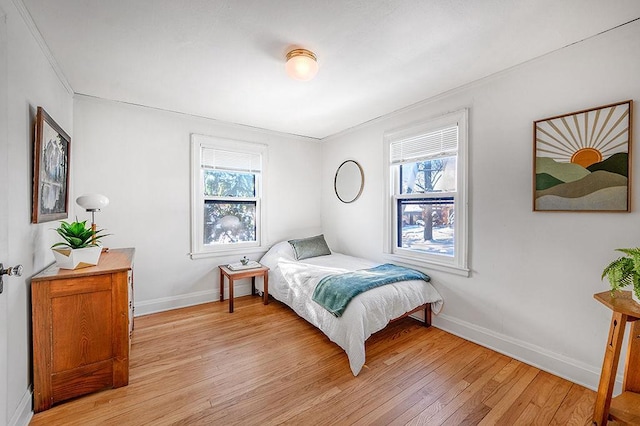 bedroom with multiple windows, baseboards, and light wood-style floors