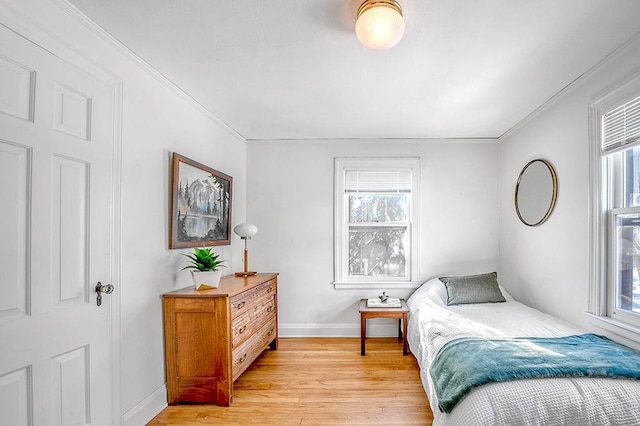 bedroom with multiple windows, baseboards, light wood-type flooring, and ornamental molding