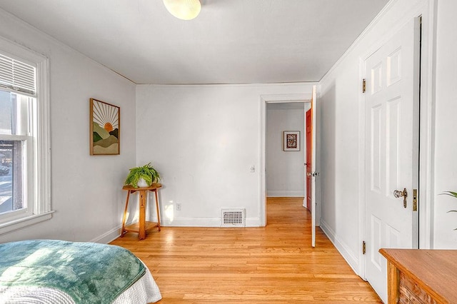 bedroom with light wood-type flooring, visible vents, and baseboards