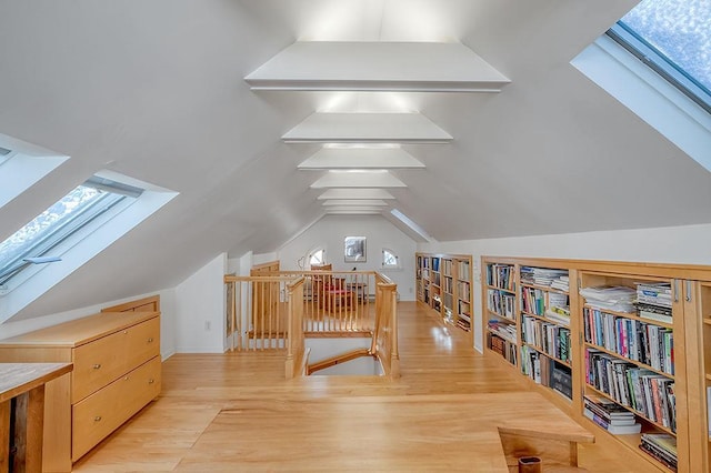 bonus room with vaulted ceiling with skylight and light wood-style floors