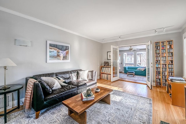 living room with baseboards, light wood-style flooring, rail lighting, french doors, and crown molding