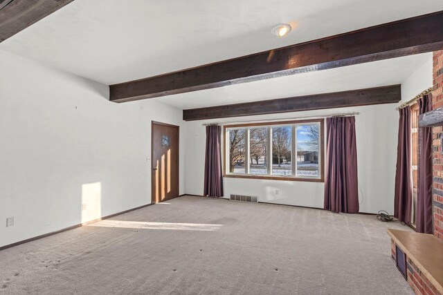 empty room with visible vents, beam ceiling, baseboards, and carpet flooring