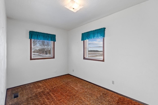 carpeted empty room featuring visible vents and baseboards
