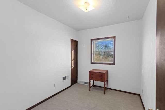 empty room featuring light carpet, visible vents, and baseboards