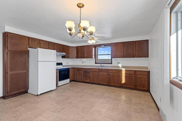 kitchen featuring under cabinet range hood, light countertops, freestanding refrigerator, electric range, and a sink
