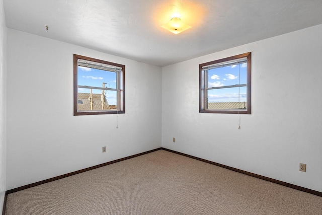 spare room with light colored carpet and baseboards