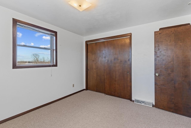 unfurnished bedroom featuring a closet, visible vents, light colored carpet, and baseboards